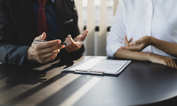 two people sit at a desk with paper between them