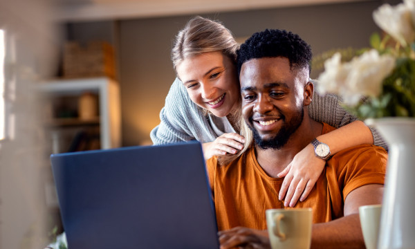a happy couple look at a laptop screen together