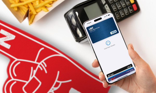 a hand holds a phone over a payment machine that lays next to a number 1 foam finger