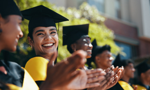 a group of graduates sit together clapping