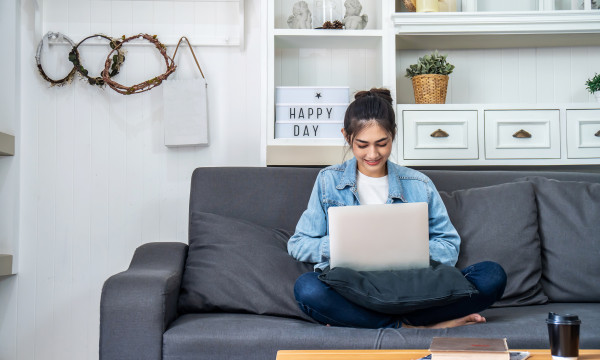 a woman sits on a couch with a laptop on her lap