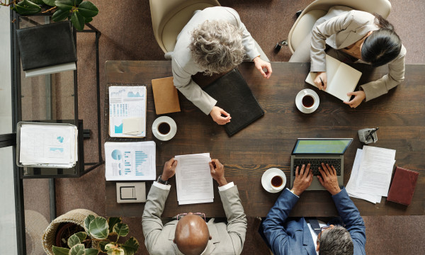 An overhead shot of 4 people having a meeting at a wooden table