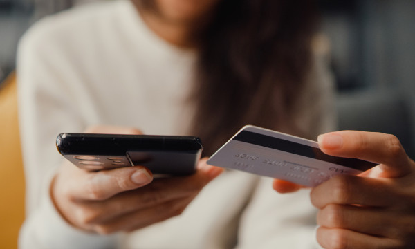 a person holds their debit card near their phone