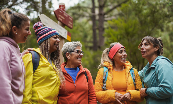 a group of women stand together outside in hiking gear laughing