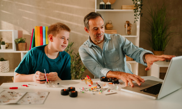 a father and son sit together at a laptop