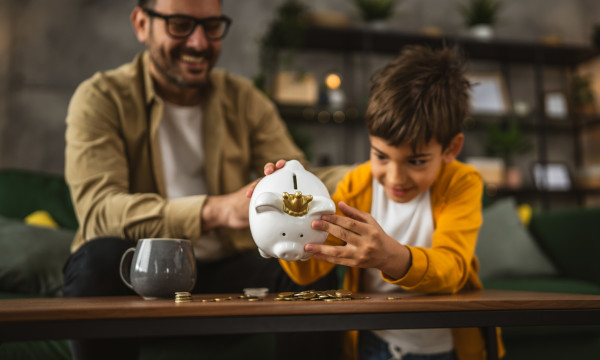 a dad and son dump out a piggy bank onto a coffee table