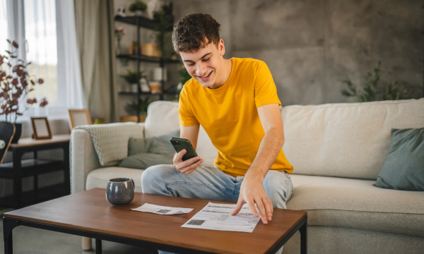 A young boy sitting on the couch and looking at his phone
