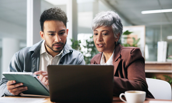 a man and woman sit together looking at a laptop